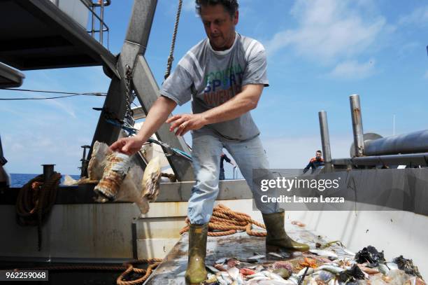 Fisherman divides the fish from the plastic waste inside the nets on a fishing boat during the operations of 'Arcipelago Pulito ' project in the...