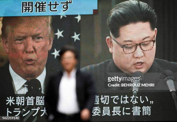 Pedestrian walks in front of a screen in Tokyo on May 25, 2018 flashing a news report relating to US President Donald Trump cancelling his meeting...