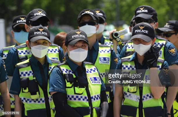 Police officers wearing face masks stand guard during a rally by anti-Trump protesters near the US embassy in Seoul on May 25, 2018. South Korea's...