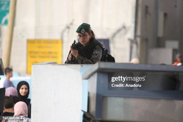 Member of Israeli security forces stands guard as Palestinian women and children cross Qalandiya checkpoint to perform second Friday Prayer of...