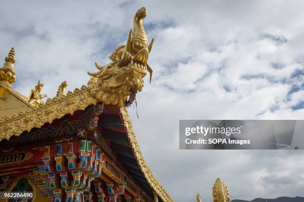 Golden rooftops of the Ganden Sumtsenling Monastery in Shangri-La surrounded by mountains.