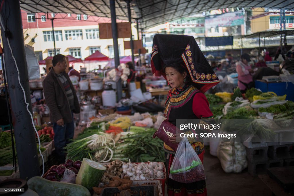 A woman wearing traditional clothes seen buying vegetable at...