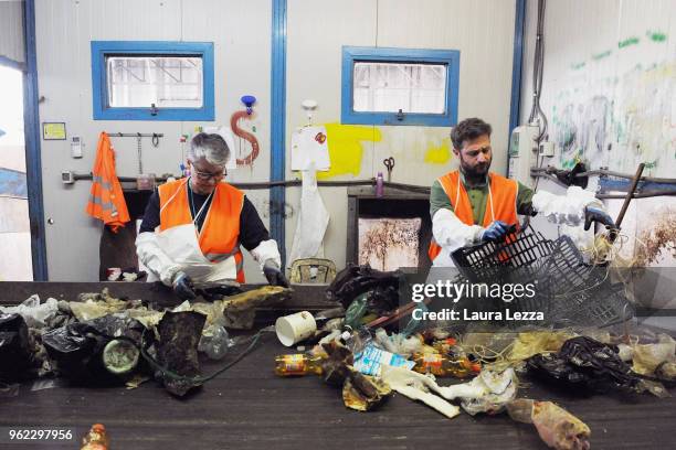 Workers in the company Revet Recycling select the plastic waste collected by the fishermen inside the nets on a fishing boat during the operations of...