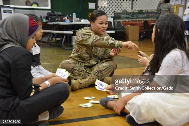 Army Private Jessica Camacho playing cards with children, waiting for treatment during Operation Empower Health at the Garden City Recreational...