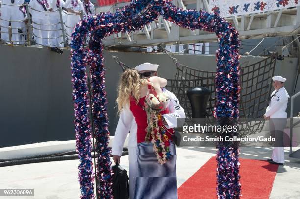 Photograph of a couple embracing in front of the guided-missile destroyer USS Halsey, recently returned from a seven-month deployment, May 14, 2018.