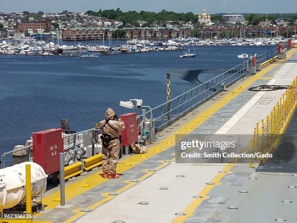 Photograph of a National Guard service member wearing a hazmat suit onboard a navy ship during Vigilant Guard training exercises concerned with...