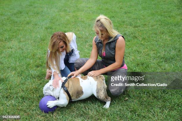 Photograph of WWE wrestlers Dana Warrior and Lacey Evans playing with the bulldog Chesty XIV, official Marine Corps mascot, during a tour of barracks...