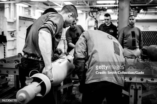 Photograph of French sailors working with American counterparts in a simulated bomb build aboard the aircraft carrier USS George HW Bush, as part of...