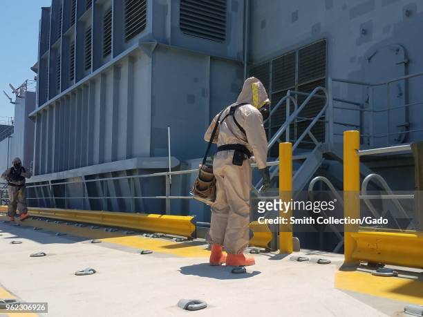 Photograph of two National Guard service members wearing a hazmat suit onboard a navy ship during Vigilant Guard training exercises concerned with...