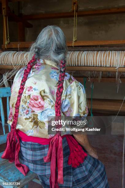 An old Zapotek woman is preparing a loom for weaving a carpet at a weavers home studio in Teotitlan del Valle, a small town in the Valles Centrales...