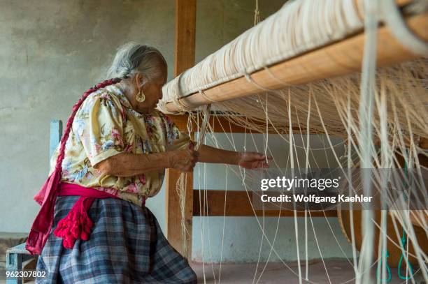 An old Zapotek woman is preparing a loom for weaving a carpet at a weavers home studio in Teotitlan del Valle, a small town in the Valles Centrales...