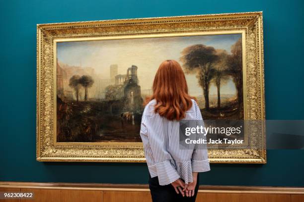 Tate employee poses in front of William Turner's 'Caligula's Palace and Bridge' during a photo call at Tate Britain on May 25, 2018 in London,...