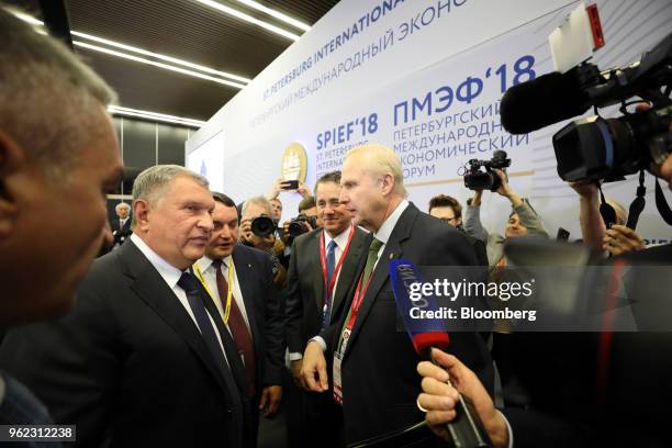 Igor Sechin, chief executive officer of Rosneft PJSC, left, and Bob Dudley, chief executive officer of BP Plc, center right, stand amidst television...