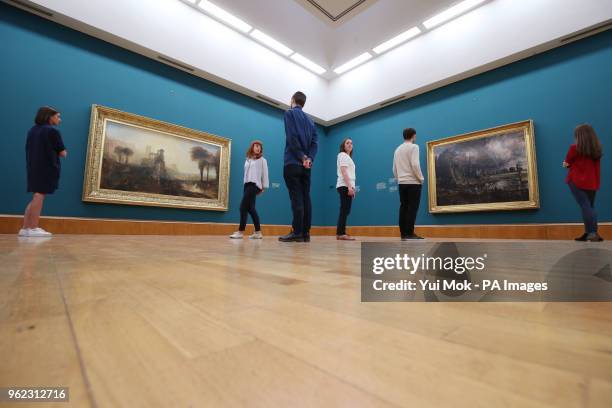 Gallery staff looking at Joseph Mallord William Turner's Caligula's Palace and Bridge and John Constable's Salisbury Cathedral from the Meadows...