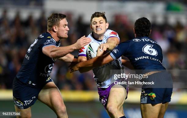 Ryley Jacks of the Storm is tackled by Coen Hess and Te Maire Martin of the Cowboys during the round 12 NRL match between the North Queensland...