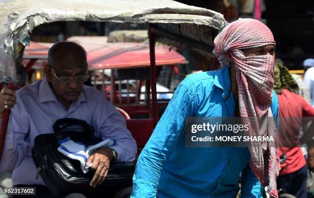 An Indian rickshaw puller covers his face to protect himself from heat during a hot summer day in the old quarters of New Delhi on May 25, 2018.