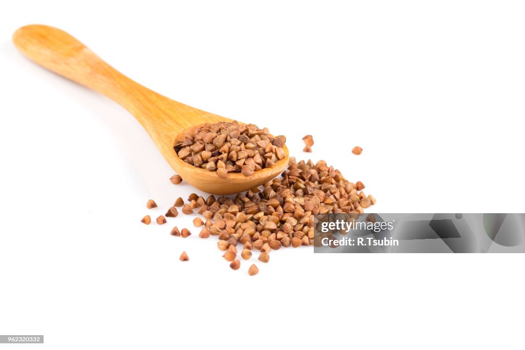 Uncooked buckwheat on wooden spoon. premium buckwheat groats on white background