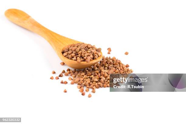 uncooked buckwheat on wooden spoon. premium buckwheat groats on white background - buckwheat stock pictures, royalty-free photos & images