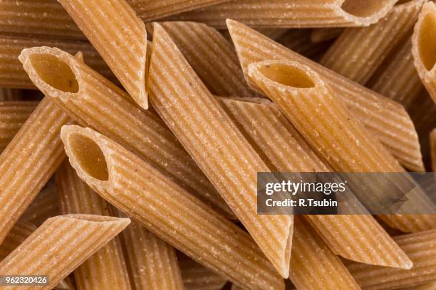 wholemeal pasta penne as close-up shot for background - grão integral imagens e fotografias de stock