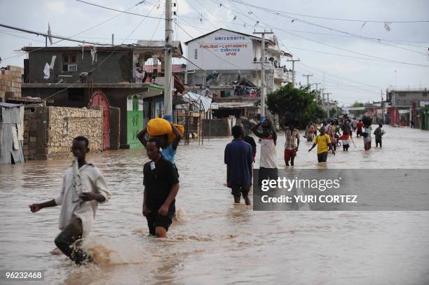 People holding some of their belongings walks during a massive exodus of the flooded city of Gonaives some 200 kilometres north of Port Au Prince on...