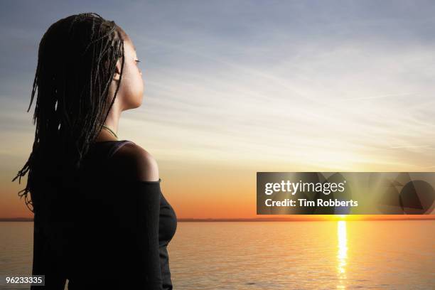 young woman looking towards sunset. - vista trasera de tres cuartos fotografías e imágenes de stock