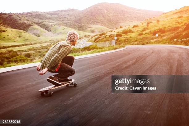 man longboarding on mountain road - speed skating photos et images de collection