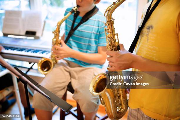 boys practicing saxophones at home - sassofono foto e immagini stock