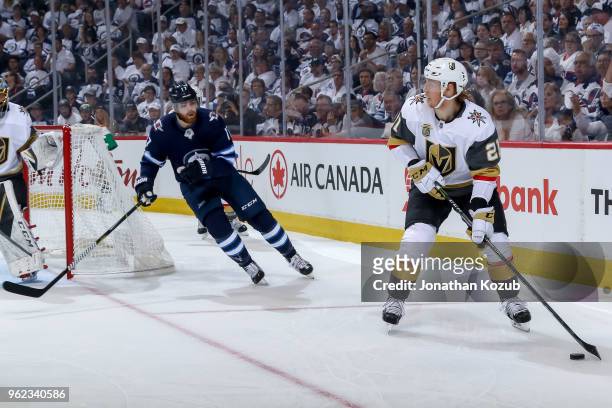 Cody Eakin of the Vegas Golden Knights plays the puck along the boards as Adam Lowry of the Winnipeg Jets gives chase during first period action in...
