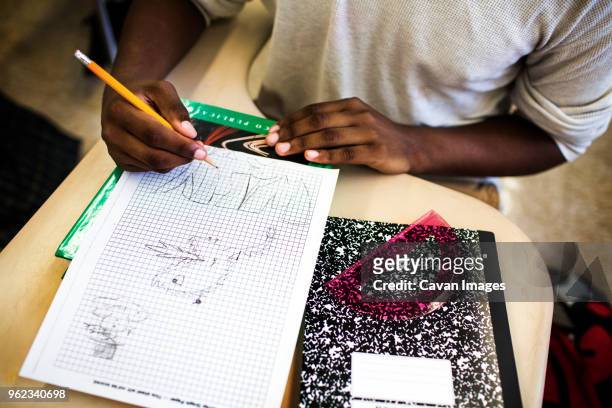 high angle view of teenage boy drawing on graph paper in classroom - graph paper stock pictures, royalty-free photos & images