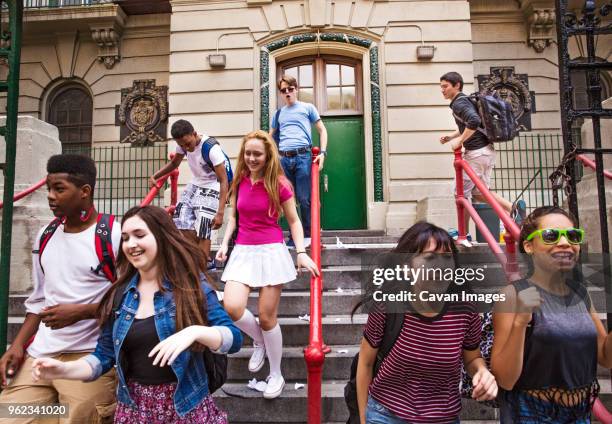 happy students moving down on steps outside high school - high school building entrance stock pictures, royalty-free photos & images