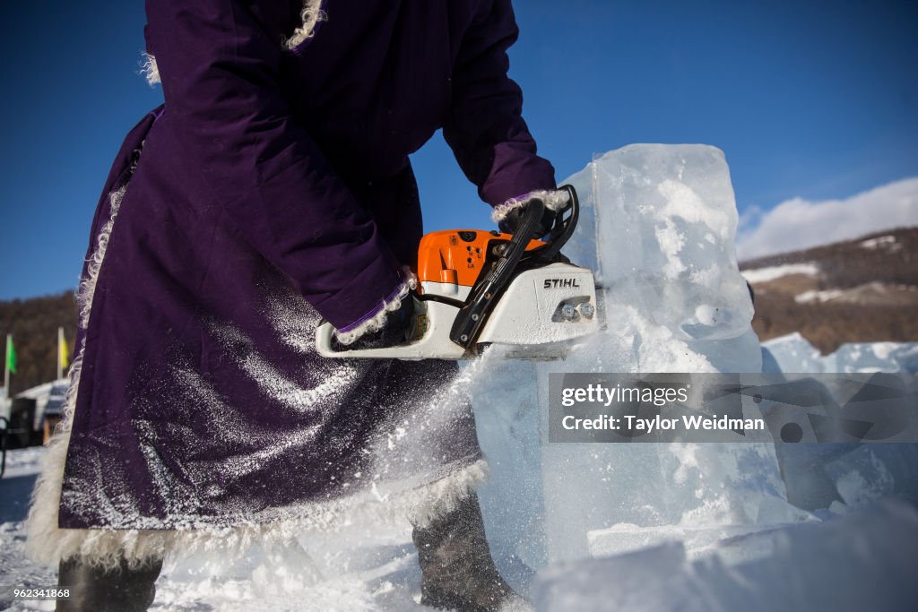 A Mongolian man cuts blocks of ice with a chainsaw at the...