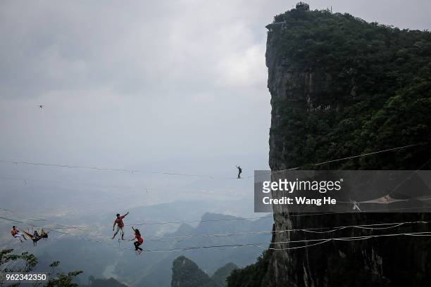 The Members of the band HouleDouse perform on slacklines across the 1,400-meter-high cliffs of Tianmen Mountain on May 25,2018 in Zhangjiajie, Hunan...