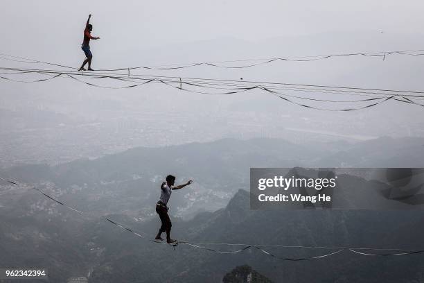 The Members of the band HouleDouse perform on slacklines across the 1,400-meter-high cliffs of Tianmen Mountain on May 25,2018 in Zhangjiajie, Hunan...