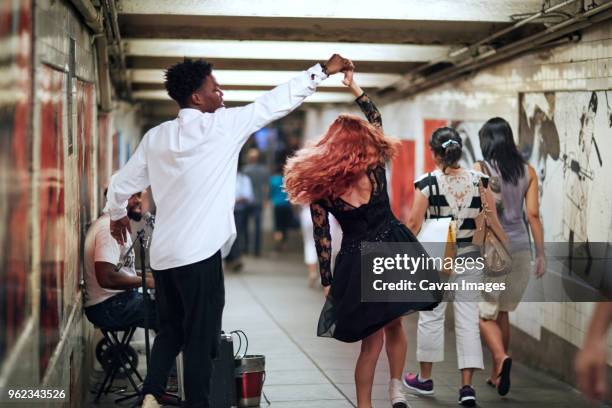 happy couple dancing while street musician singing in subway - busker ストックフォトと画像