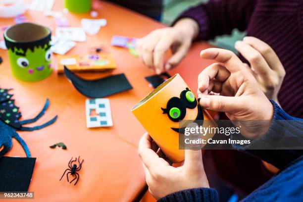 cropped image of boy making smiley face decoration at table during halloween party - smiley face stock pictures, royalty-free photos & images