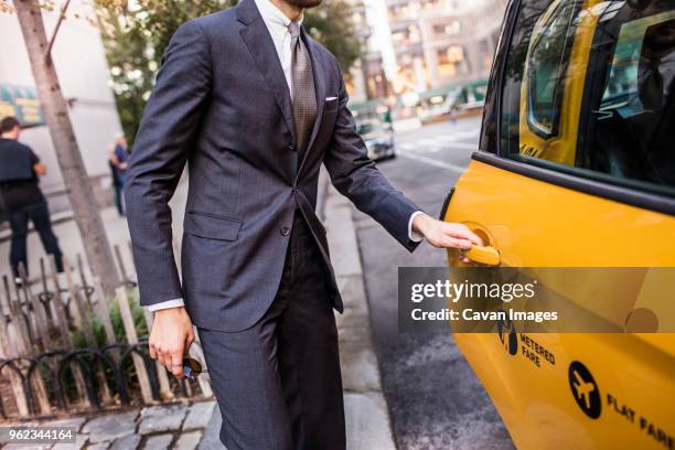 midsection of businessman opening taxi door on city street - yellow taxi 個照片及圖片檔