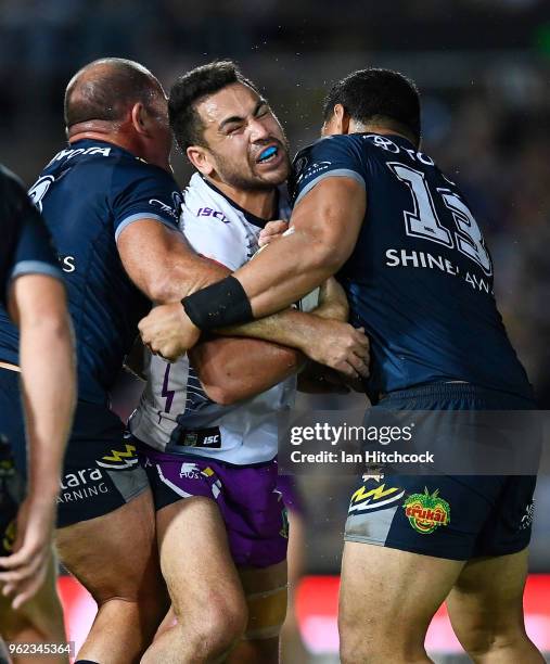 Jahrome Hughes of the Storm is tackled by by Matthew Scott and Jason Taumalolo of the Cowboys during the round 12 NRL match between the North...