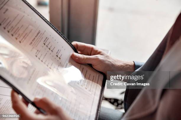 cropped image of man holding menu while sitting in restaurant - menú fotografías e imágenes de stock
