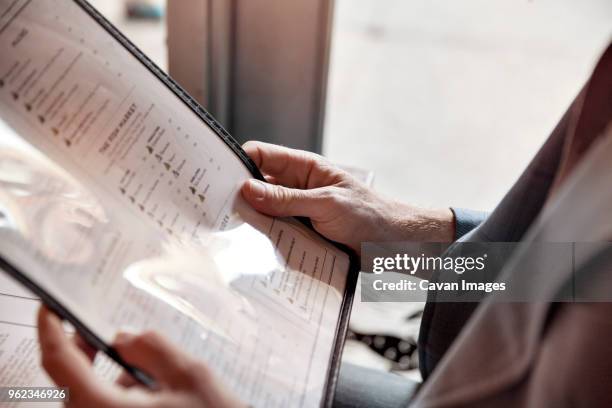 cropped image of man holding menu while sitting in restaurant - ementa imagens e fotografias de stock
