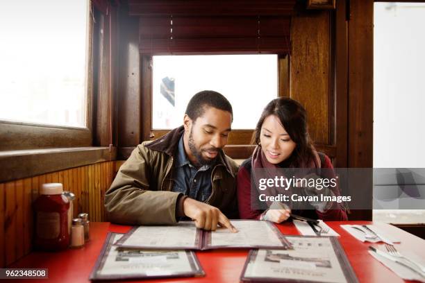 couple looking at menu while sitting in restaurant - menu stock pictures, royalty-free photos & images