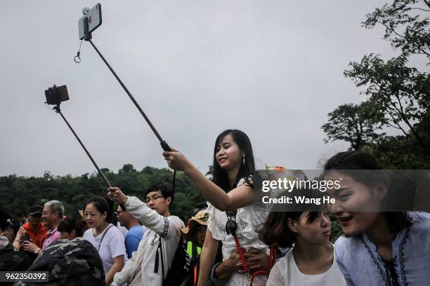 The tourists use selfie sticks to take pictures with their phones as the band HouleDouse perform on slacklines across the 1,400-meter-high cliffs of...