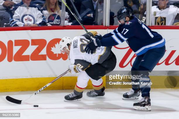 Tomas Nosek of the Vegas Golden Knights plays the puck along the boards as Adam Lowry of the Winnipeg Jets gives chase during second period action in...