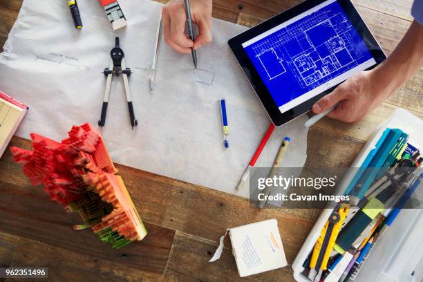 cropped image of architect drawing blueprints while holding tablet computer at office - my tablet tool stock pictures, royalty-free photos & images