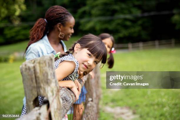 girls with teacher standing by fence at field trip - portrait of school children and female teacher in field stock pictures, royalty-free photos & images