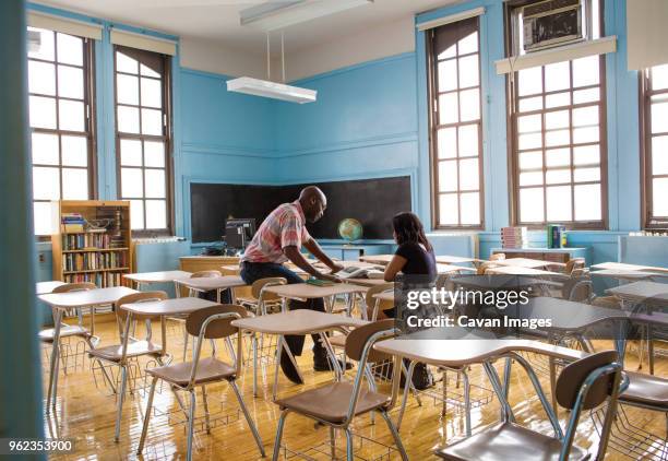 teacher and student reading book while sitting in classroom - cavan images stockfoto's en -beelden