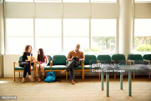 patients sitting on chairs in waiting room - hospital waiting room stockfoto's en -beelden