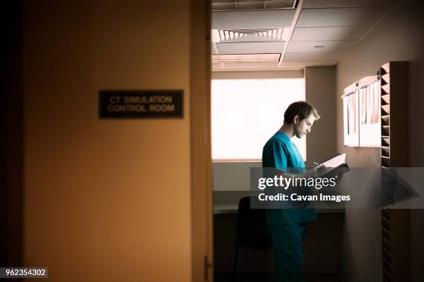 doctor reading reports while standing in hospital ward - doctor reading stock pictures, royalty-free photos & images