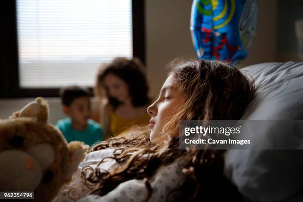 patient relaxing on bed with family in backgrounds - sibling hospital stock pictures, royalty-free photos & images