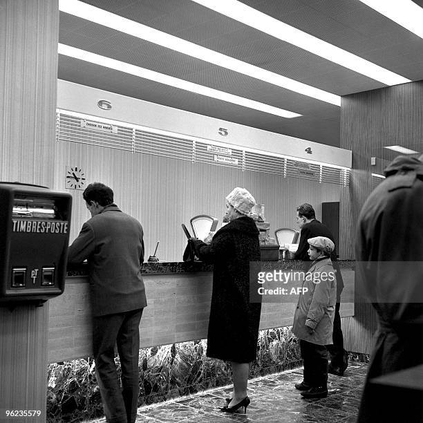 Des usagers attendant leur tour aux guichets du bureau de poste des Champs-Elysées à Paris le 29 mars 1962. Le bureau de poste vient de rouvrir ses...