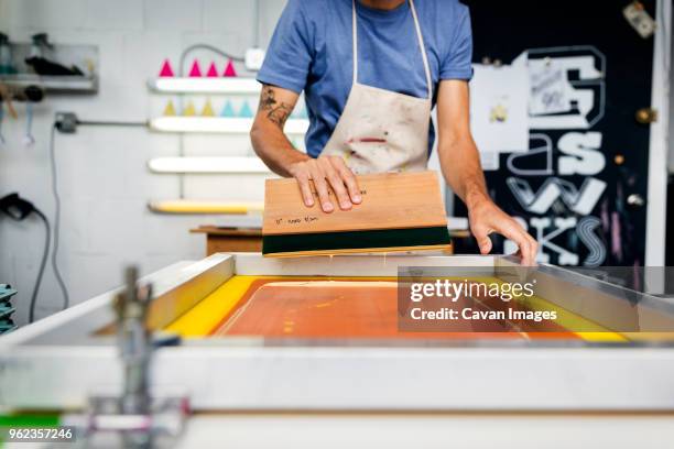 midsection of man working on silk screen in workshop - siebdruck stock-fotos und bilder